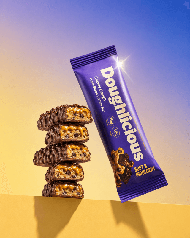 Flatlay of a cookie dough protein bar beside a stack of coated bars