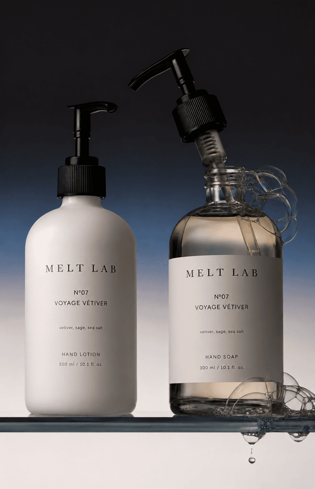 Duo of hand lotion and hand soap bottles on a glass shelf