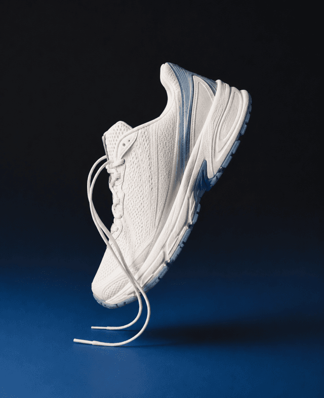 Product shot of a white running sneaker on a moody blue backdrop